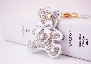 Close-up of a white leather bear keychain featuring shiny rhinestones and a 3D bow accent