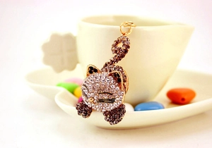 Détail d'un porte-clés chat avec strass brillants sur le bord d'une tasse à café