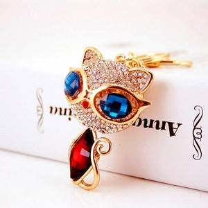 Portachiavi gatto dorato con strass bianchi brillanti e un grande cristallo rosso a goccia