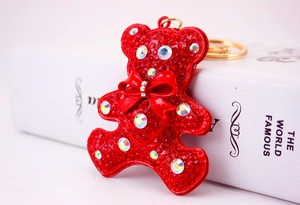 Macro detail of red rhinestone teddy bear keychain with shimmering bow and golden clasp