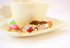 Détail d'un porte-clés voiture de sport doré avec strass sur une soucoupe en céramique