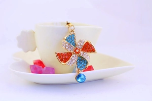 Detailed close-up of a crystal windmill keychain hanging on a white ceramic coffee cup