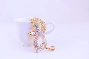 Détail d'un porte-clés masque de cristal avec gemmes orange sur le bord d'une tasse