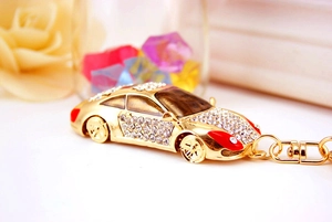 Gros plan d'un porte-clés voiture doré orné de strass blancs et détails rouges