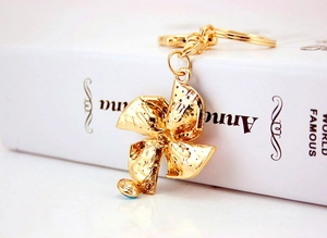 Detailed side view of golden windmill keychain with blue crystal accents on white book