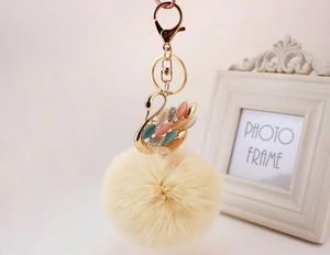 Dettaglio portachiavi a cigno con pietre occhio di gatto e pompon beige soffice