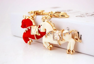 Dettaglio di portachiavi a forma di cavallo con strass e finiture dorate rosse e crema