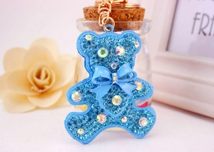 Detailed close-up of blue rhinestone teddy bear keychain with gold ring and bow