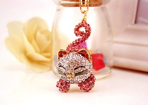 Détail du porte-clés chat endormi en strass roses avec fermoir doré sur fond fleuri