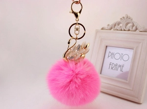 Dettaglio del portachiavi con pompon in ecopelliccia rosa e ciondolo a cigno dorato