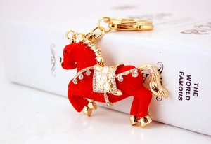 Dettaglio di un portachiavi a forma di cavallo rosso floccato con accenti dorati e strass