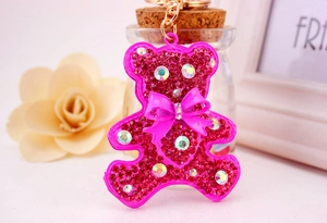 Close-up of bright pink rhinestone bear keychain with a glittery bow and gold clasp