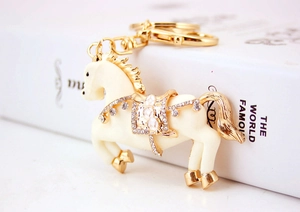 Dettaglio portachiavi a forma di cavallo dorato con strass e smalto color crema