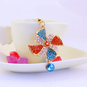 Colorful crystal windmill keychain with rhinestones and blue pendant on white ceramic cup