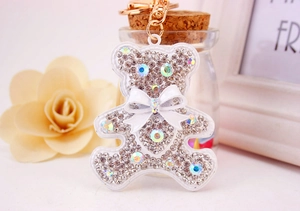 Detail of white rhinestone bear keychain with crystal bow and gold lobster clasp charm