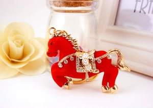 Dettaglio del portachiavi a forma di cavallo floccato rosso con accenti dorati e strass
