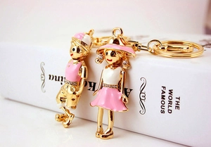 Detail of cartoon couple keychains with gold plating, pink enamel and crystal accents