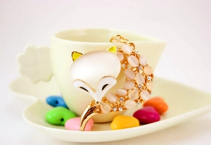 Detail eines vergoldeten Fuchs-Anhängers mit Opal-Kopf und rosa Strasssteinen am Schwanz