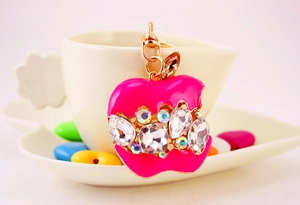 Détail d'un porte-clés pomme en cristal rose avec strass colorés sur une tasse