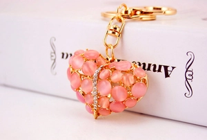 Detail van gouden hart sleutelhanger met roze opaalstenen en fonkelende strass steentjes