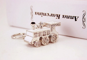 Creative silver train keychain with sparkling crystals and white enamel on a book