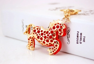 Dettaglio di un portachiavi a forma di cavallo dorato con strass su un libro bianco