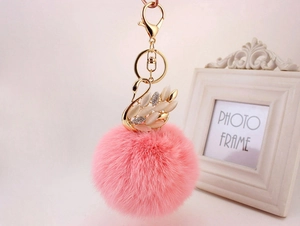 Dettaglio portachiavi con pompon rosa e ciondolo a forma di cigno dorato con strass