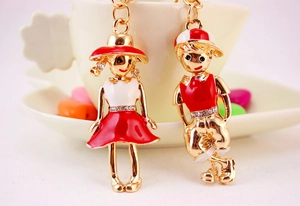 Detail of couple cartoon keychains featuring gold alloy with red enamel and rhinestones