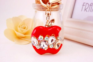 Détail d'un porte-clés pomme rouge avec cristaux brillants et chaîne dorée élégante