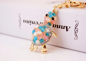 Macro view of crystal rhinestone turtle keychain with pink cat eye stone and gold alloy