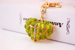 Detail van hartvormige sleutelhanger met groene opaalstenen en witte strass op goud