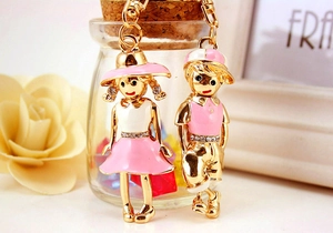 Detail of cute couple boy and girl metal keychains with pink enamel and small rhinestones