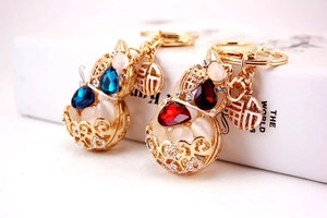 Detailed view of hollow gold gourd keychains with blue and red gems and opal stones