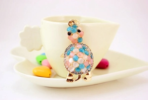 Close-up of golden turtle keychain with pink rhinestones hanging on a coffee cup