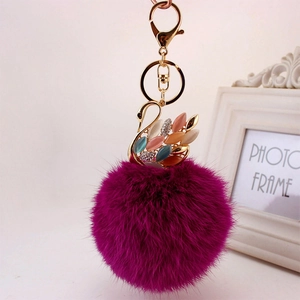 Portachiavi con pompon in pelliccia viola e ciondolo a forma di cigno dorato con strass