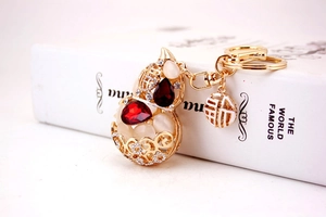 Detailed view of golden gourd keychain with red crystals, opal stone, and Fu charm