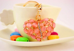 Detail van hartvormige sleutelhanger met roze opaalstenen en strass op gouden basis
