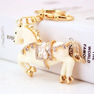 Portachiavi a forma di cavallo con smalto bianco e strass su un libro bianco