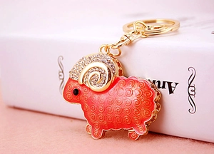 Close-up of golden goat keychain with red enamel patterns and sparkling rhinestones