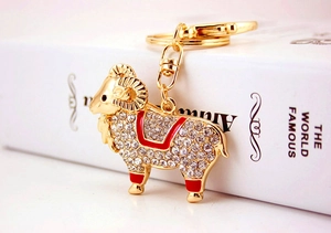 Gros plan du porte-clés chèvre dorée avec strass brillants et émail rouge élégant