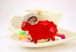 Detail of cute sheep keychain with red enamel and sparkling rhinestones on golden alloy