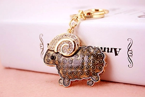 Close-up of golden goat keychain with enamel spiral patterns and sparkling rhinestones