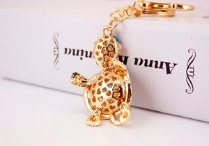 Detail of golden turtle keychain with heart cutouts and colorful beads inside
