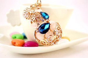Detailed close-up of golden hollow gourd keychain with blue crystals and opal stones