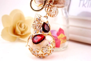 Macro detail of gold hollow gourd keychain with red crystals and lucky charm pendant