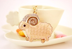 Close-up of pink enamel sheep keychain with rhinestones hanging on a ceramic cup