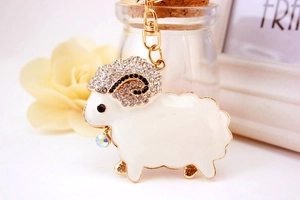 Macro shot of white enamel sheep keychain with rhinestones and colorful crystal drop