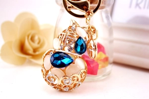 Macro detail of a golden gourd keychain with blue rhinestones and Fu character engraving