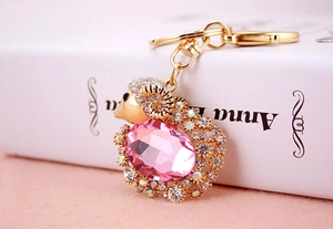 Detailed close-up of crystal goat keychain with pink gemstone and gold plating