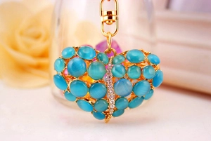 Detail van hartvormige sleutelhanger met blauwe opaal kralen en strass in goud